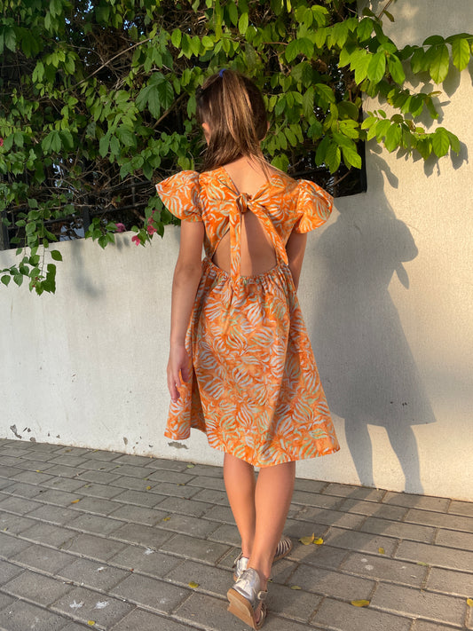 Back view of Ivy orange tiger lily cotton batik dress, handmade sustainably in Bali by local artisans, featuring ruffle sleeves, adjustable back ties, and an a-line fit, perfect for outings in Dubai!