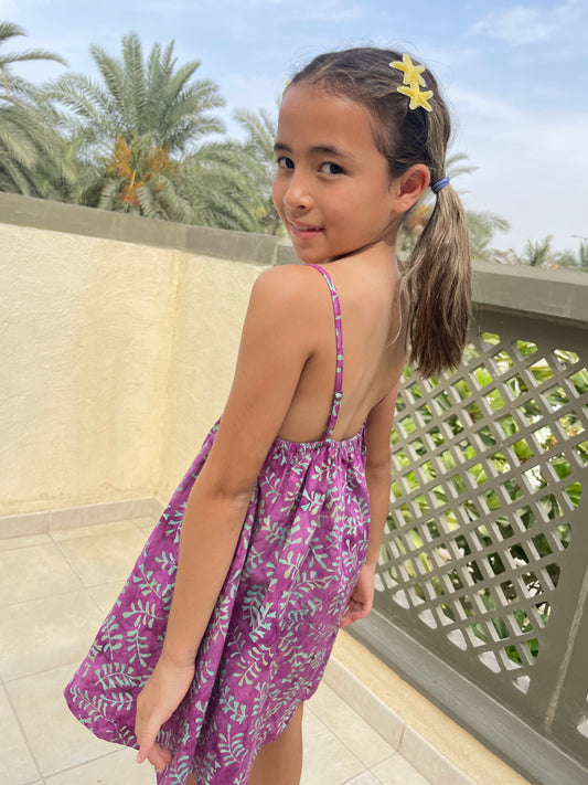 Back close up view of the Millie kids sundress handmade by artisans in Bali, featuring hand-stamped cotton batik in bright purple and aquamarine, with adjustable waist and spaghetti straps, for fashion loving little ones in Dubai