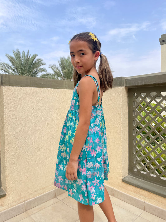 Back view of our Millie girls cotton dress made from green floral batik, artisan-made fabric from Indonesia, sustainably made fashion for girls in Dubai, featuring a-line fit, elastic waistband, and adjustable shoulder straps for perfect fit that grows with you child.