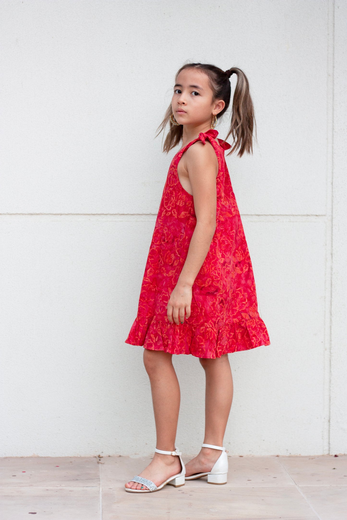 Penelope hand-stamped Indonesian cotton batik red knee-length a-line kids dress with adjustable rabbit ear shoulder ties for fashionable little girls in Dubai, sustainably made in Bali