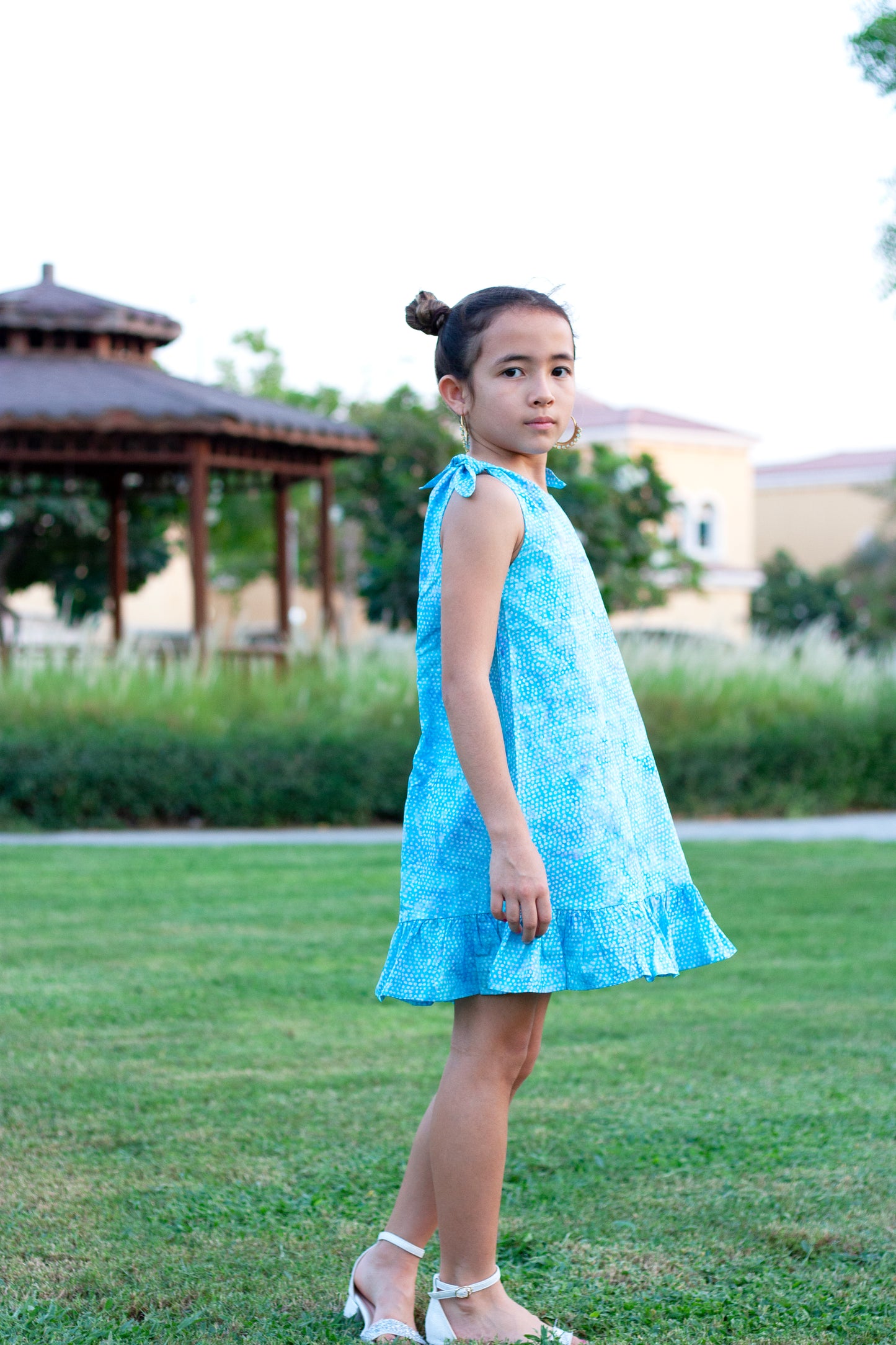 Shop sustainably with the Penelope Girls Batik Sundress in Blue Polka Dots. Hand-stamped batik, A-line silhouette, and adjustable ties. Perfect summer dress for girls in Dubai!