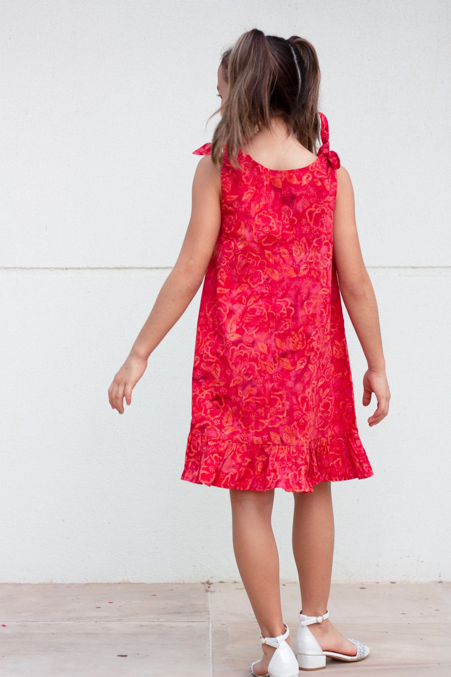 Back view Penelope hand-stamped Indonesian cotton batik red knee-length a-line kids dress with adjustable rabbit ear shoulder ties and ruffle hem, perfect for fashionable little girls in Dubai, sustainably made in Bali