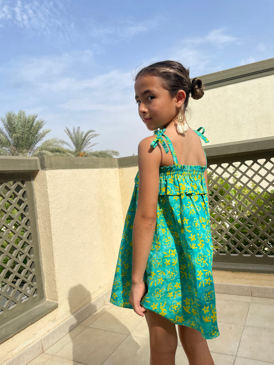 Back view of Rory batik cotton dress in green & yellow floral, hand-stamped artisanal batik from Indonesia, paired with cream tassel earrings, sustainably handmade in Bali, available in Dubai at WildFabrik