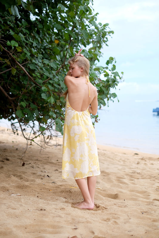 Back view of Mimi lightweight crepe chiffon yellow floral beach dress with low back, neck ties, adjustable waist, and a flowing silhouette, perfect for chill afternoons in Dubai.