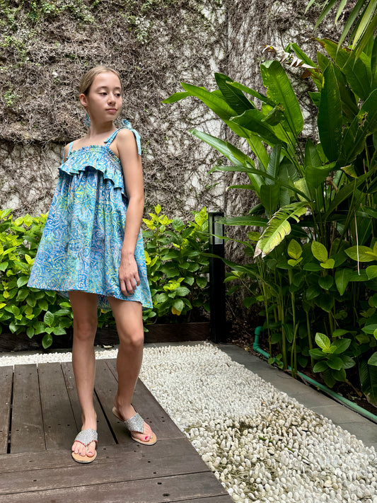 Handmade kids sundress in sustainably made cotton with intricate Indonesian batik hand-dyed paisley print, in a blue pink and yellow color palette, made in Bali, shop now in Dubai