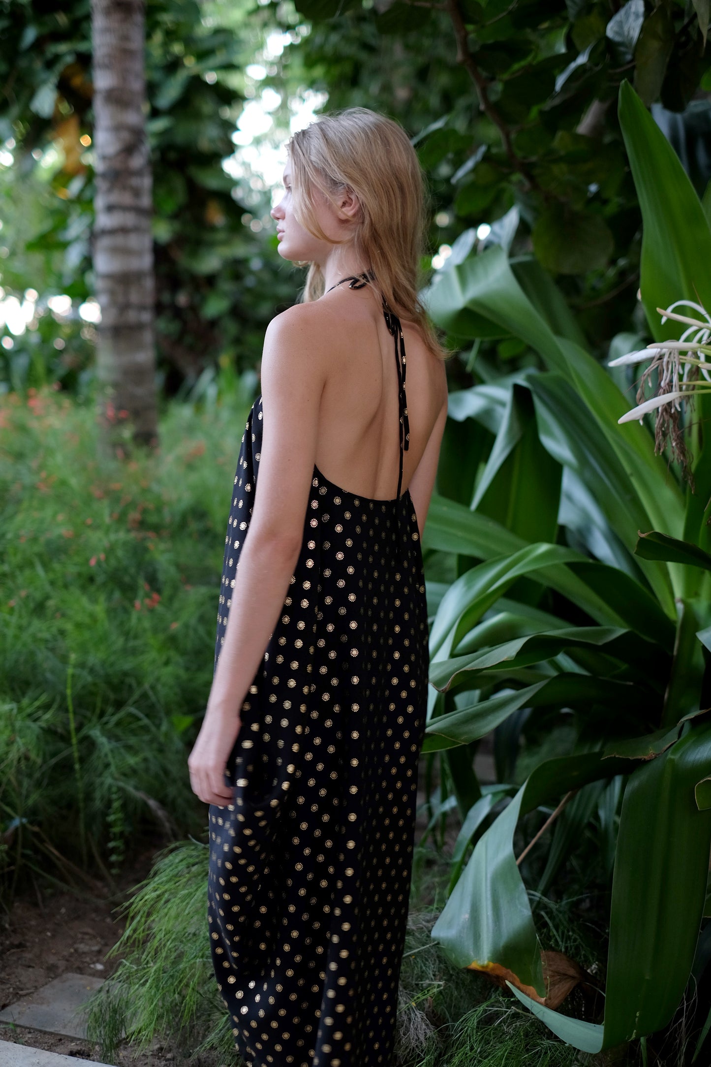 Back view of the Seraphina black and gold kaftan beach style resort wear dress with luxurious shimmering gold accents, worn as a halter dress, for glamorous beach days out in Dubai