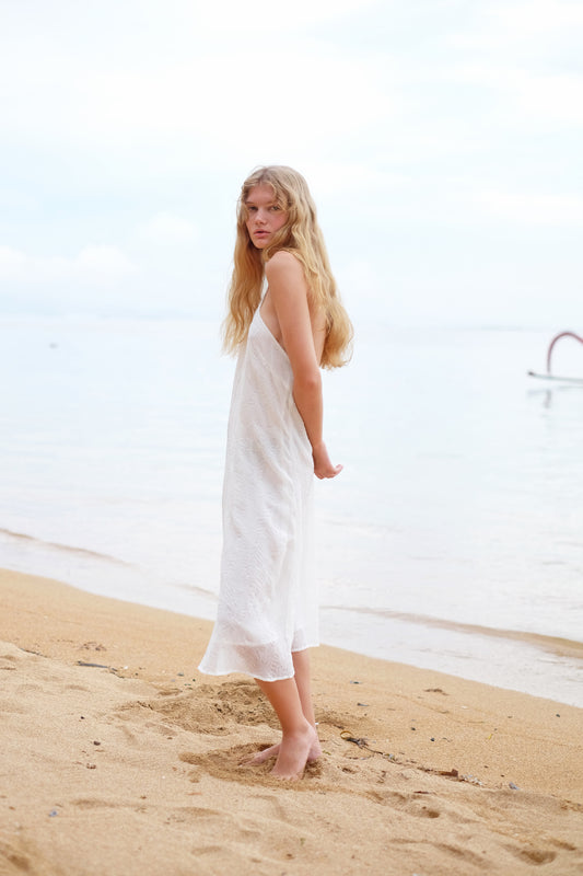 Side view of Mimi textured white midi halter dress with delicate beadwork and adjustable ties for a perfect fit.