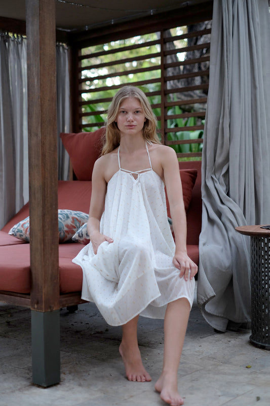 A versatile Seraphina multiway kaftan dress in white with metallic accents, worn as a halter dress, perfect for beachwear and resort styling in Dubai