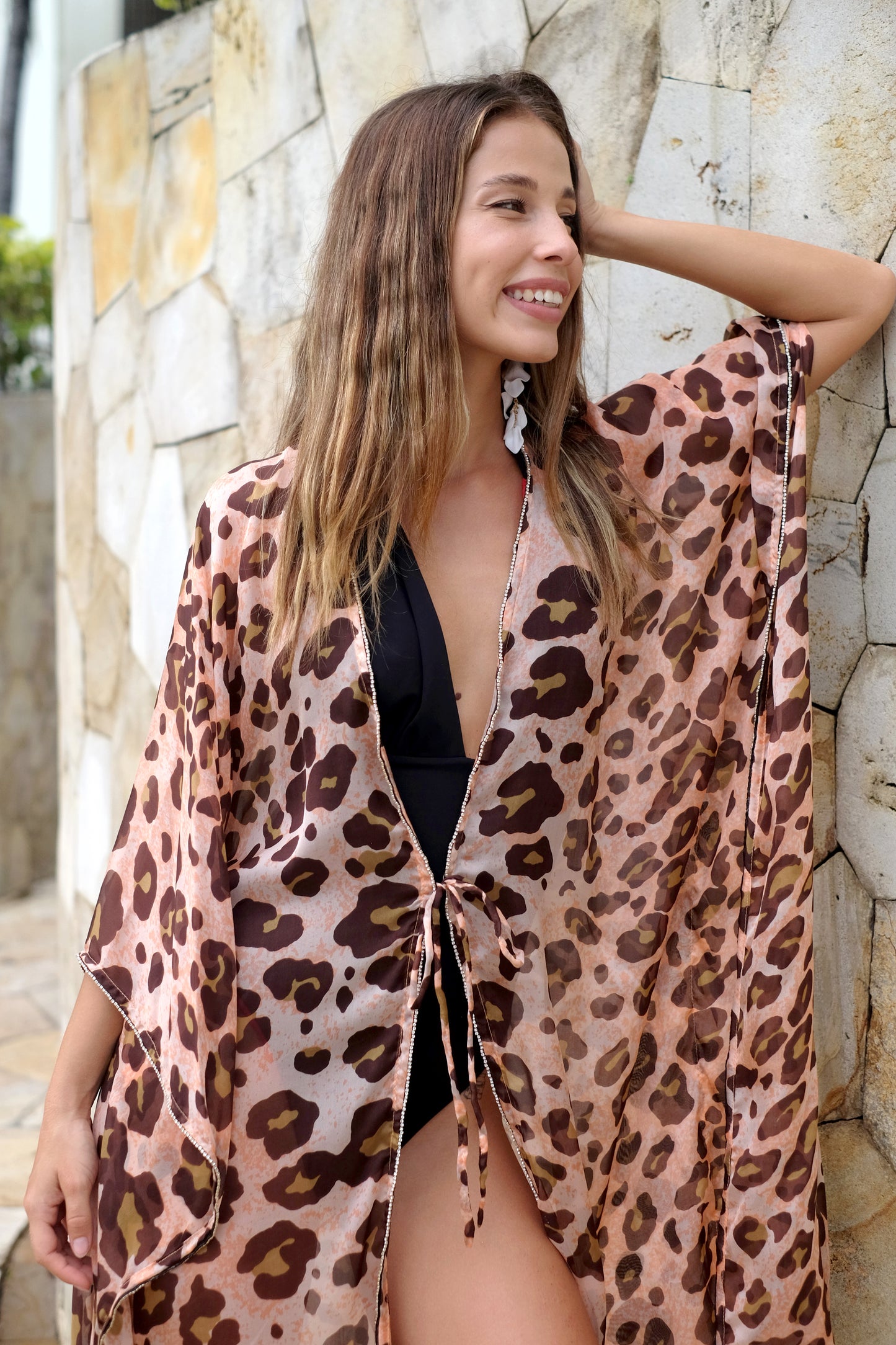 Close up of woman wearing an orange and brown leopard print silk chiffon beach kaftan for women in Dubai with rhinestone neckline and sleeve embellishments