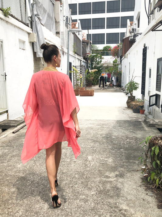 Elegant salmon pink kaftan with gold detailing, perfect for Dubai beach days and resort fashion