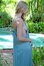 Load image into Gallery viewer, Side view of young woman wearing a maxi length halter dress in yoryo chiffon in a gorgeous sage green featuring a pleated neckline and backline with beads and adjustable neckties, sustainably made in Bali for fashionistas in Dubai