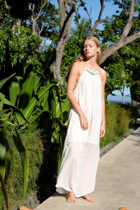 Girl wearing a long white halter neck maxi beach dress at a resort in Bali, sustainably made in Bali for fashionistas in Dubai