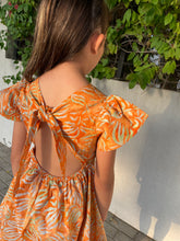 Load image into Gallery viewer, Back view of the Ivy orange tiger lily cotton batik dress, handmade sustainably in Bali by local artisans, featuring ruffle sleeves, adjustable back ties, and an a-line fit, perfect for outings in Dubai and those who love slow fashion style.