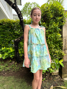 Full length front view of Layla Girls' Cotton Sundress with Hand-Stamped Batik Prints in light blue, green and yellow paisley, sustainably handmade in Bali with ruffle accents and shoulder ties for longer wear