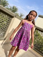 Load image into Gallery viewer, Front view of the Millie kids sundress sustainably handmade by talented artisans in Bali, featuring hand-stamped cotton batik in bright purple and aquamarine, with adjustable waist and spaghetti straps, for slow fashion lovers in Dubai