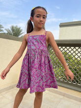 Load image into Gallery viewer, Front view of the Millie kids sundress handmade by local artisans in Bali, featuring hand-stamped cotton batik in bright purple and aquamarine, with adjustable waist and spaghetti straps, for fashion loving little ones in Dubai