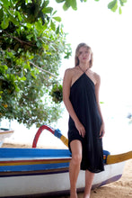 Load image into Gallery viewer, Model standing and wearing the Mimi black halter dress, showcasing its flowy silhouette and chic style perfect for any occasion.