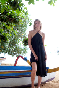 Model standing and wearing the Mimi black halter dress, showcasing its flowy silhouette and chic style perfect for any occasion.
