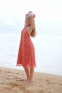 A side angle of the Mimi burnt orange midi dress, highlighting the halter neck and midi dress length, sustainable style made in Bali for women in Dubai.
