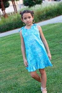 The Penelope Girls Batik Sundress in Blue Polka Dots, sustainably made in Bali. Hand-stamped batik, A-line silhouette, and adjustable ties. Perfect summer dress for girls in Dubai!