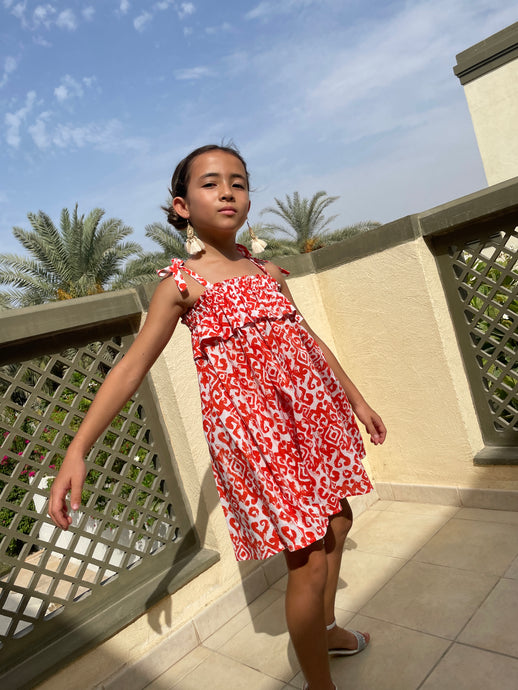 Indonesian hand-stamped orange ikat print cotton batik dress for girls in Dubai, knee length, sustainably made in Bali, paired with cream tassel earrings