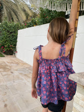 Load image into Gallery viewer, Back view close up of girl wearing purple ruffle top with shoulder ties and black shorts, the top is made from Indonesian cotton batik, available in Dubai