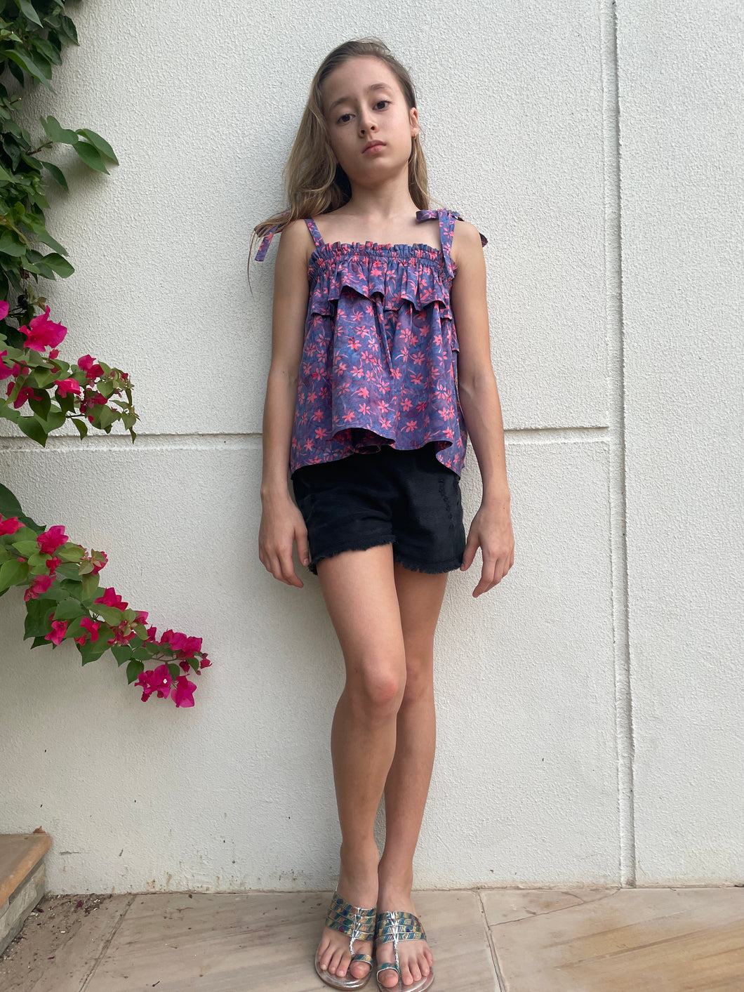 Girl wearing purple ruffle top with shoulder ties and black shorts, the top is made from Indonesian cotton batik, available in Dubai