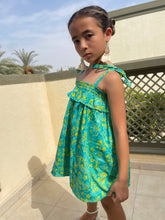 Load image into Gallery viewer, Close up front view of Rory batik cotton dress in green &amp; yellow floral, hand-stamped artisanal batik from Indonesia, paired with cream tassel earrings, sustainably handmade in Bali, available in Dubai at WildFabrik