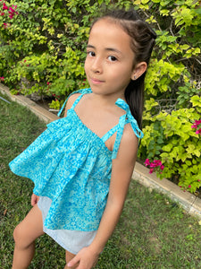 Close up photo of girl wearing light blue floral cotton batik top, with ruffles along neck and backlines, adjustable shoulder ties, can also be worn as skirt, handmade by artisans in Bali, available in Dubai