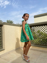 Load image into Gallery viewer, Side view of Rory batik cotton dress in green &amp; yellow floral, hand-stamped artisanal batik from Indonesia, paired with cream tassel earrings, sustainably handmade in Bali, available in Dubai at WildFabrik