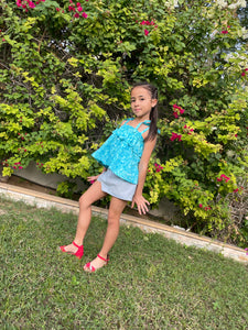 Full length photo of girl wearing light blue floral cotton batik top, with ruffles along neck and backlines, adjustable shoulder ties, can also be worn as skirt, handmade by artisans in Bali, available in Dubai