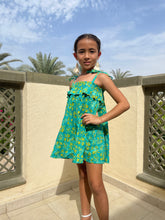 Load image into Gallery viewer, Front view of Rory batik cotton dress in green &amp; yellow floral, hand-stamped artisanal batik from Indonesia, paired with cream tassel earrings, sustainably handmade in Bali by local artisans, available in Dubai at WildFabrik