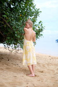 Back view of Mimi lightweight crepe chiffon yellow floral beach dress with low back, neck ties, adjustable waist, and a flowing silhouette, perfect for chill afternoons in Dubai.
