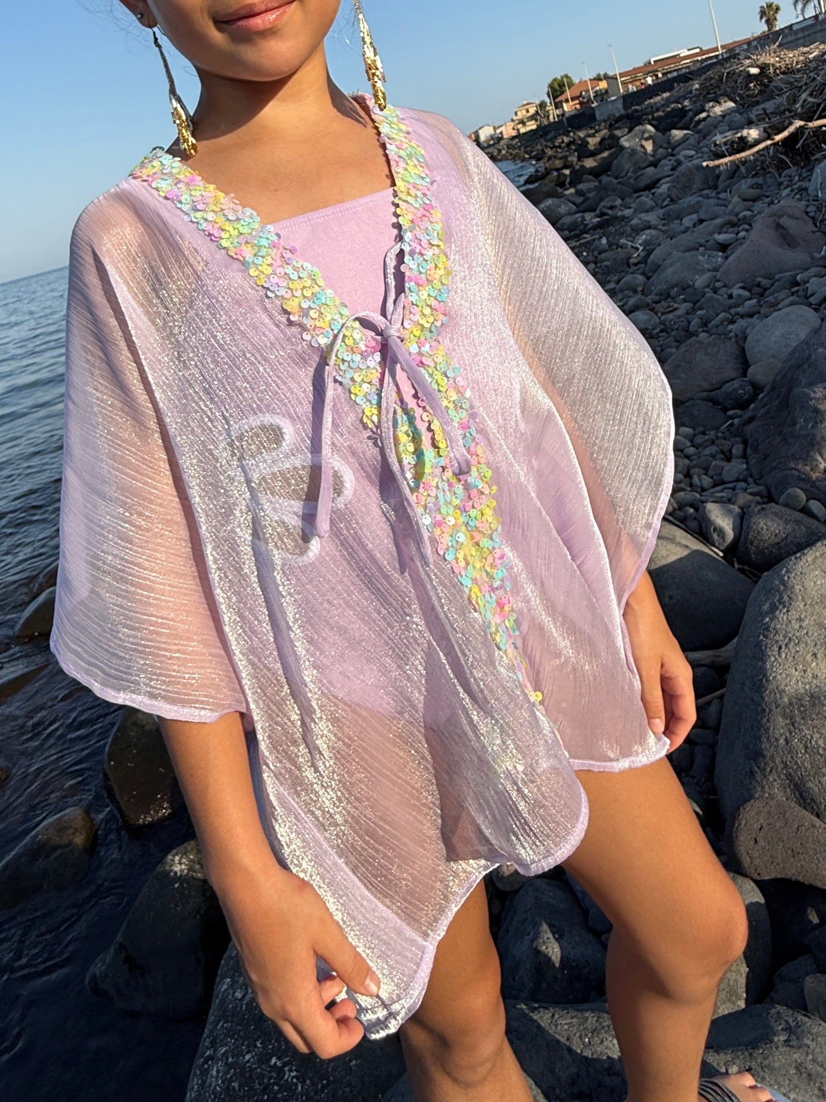 Close up of girl in shimmery purple beach kaftan with light rainbow colored sequins along the neckline, beachwear for Dubai girls 