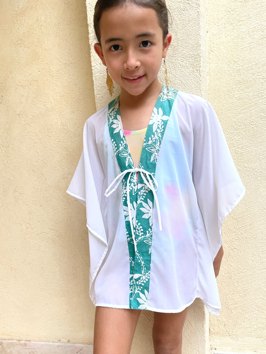 Handmade kids beach kaftan in white lurex chiffon with green floral batik trim – sustainable Dubai beachwear.
