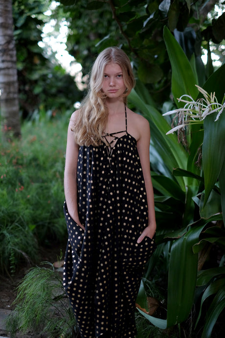 Seraphina black and gold kaftan dress with shimmering gold accents, worn as a halter style.