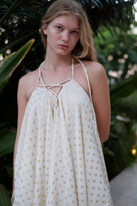 Versatile cream and gold Seraphina kaftan dress worn as a halter dress, featuring delicate gold motifs, perfect for beach resorts and evening wear in Dubai.