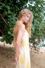 Load image into Gallery viewer, Side view of elegant midi dress in yellow floral printed chiffon, featuring adjustable neck ties and waist band for the perfect fit, styled for effortless beachside adventures in Dubai.

