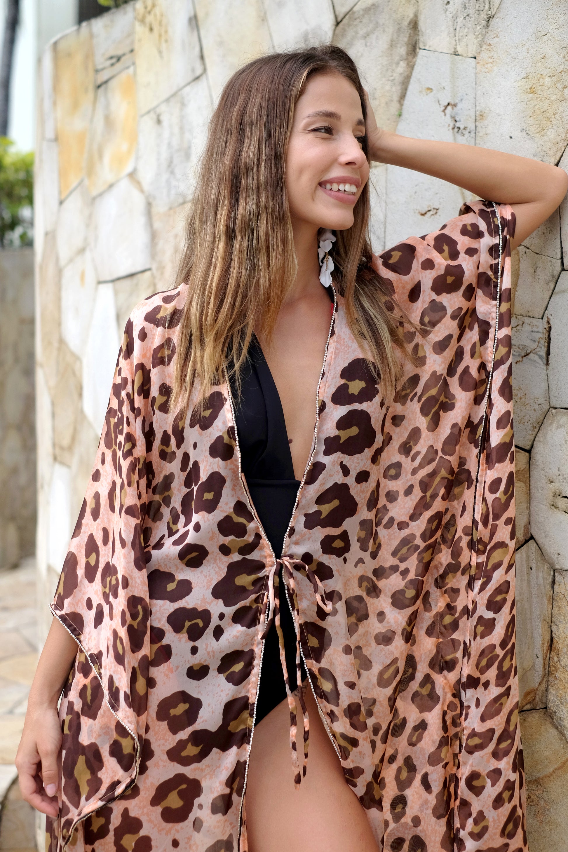 Close up of woman wearing an orange and brown leopard print silk chiffon beach kaftan for women in Dubai with rhinestone neckline and sleeve embellishments